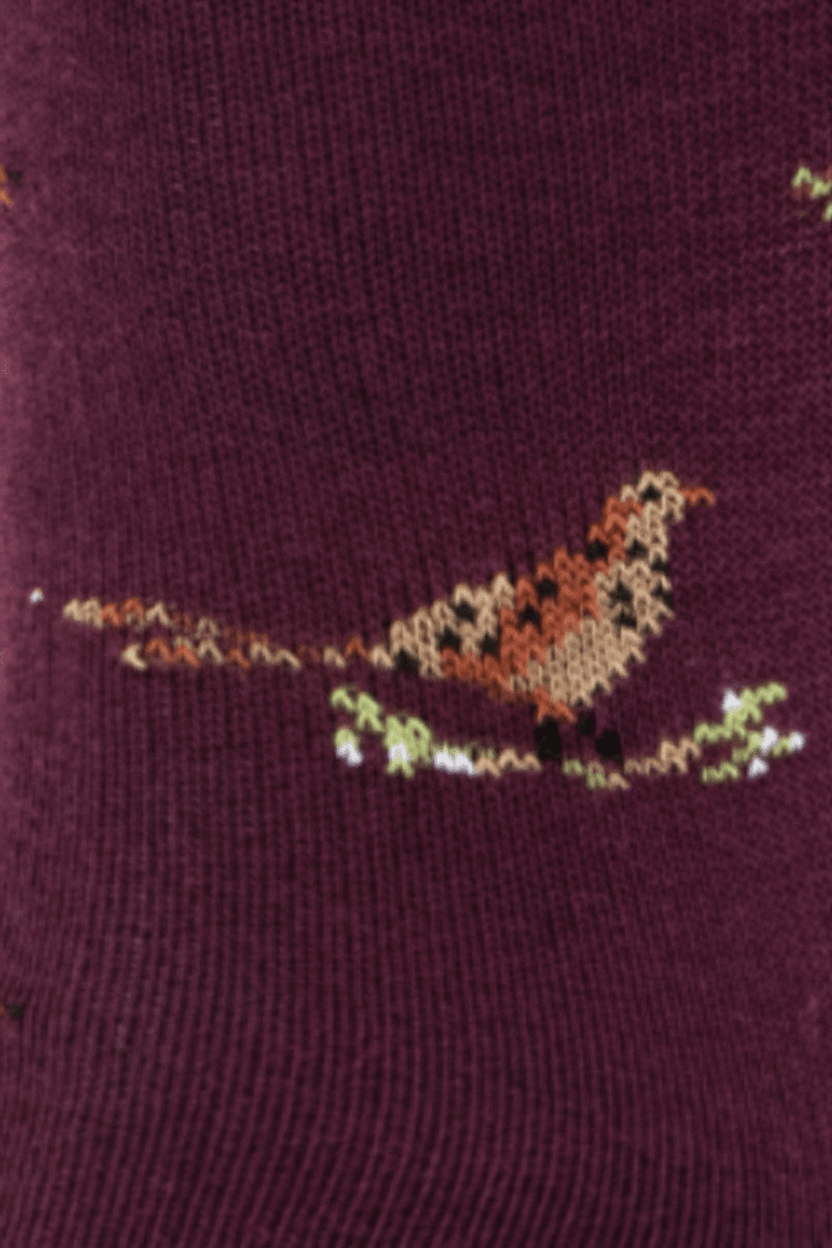 A close-up of a knit fabric in deep burgundy with a small embroidered bird motif in tan, brown, black, and light green.