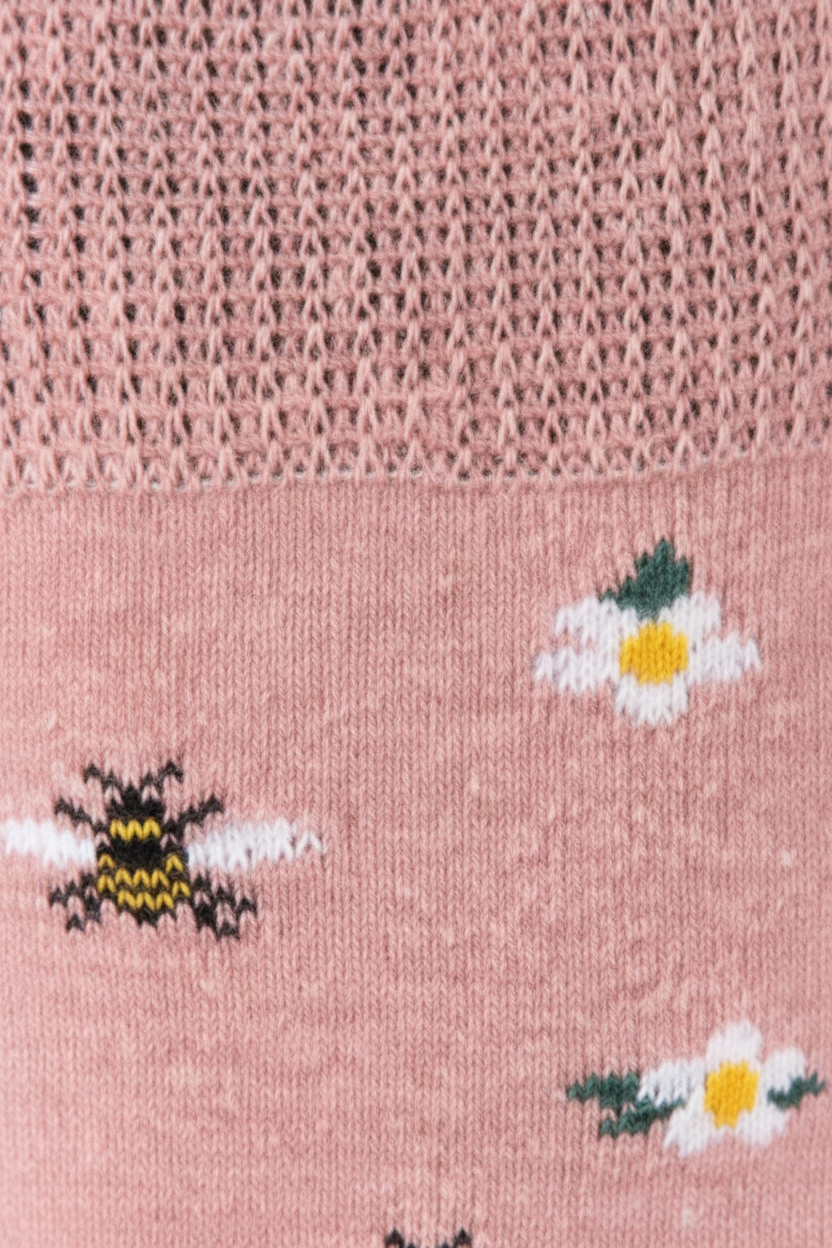 Close-up of a pink knit sock with embroidered details, including a yellow and black bumblebee and small white flowers with green leaves.