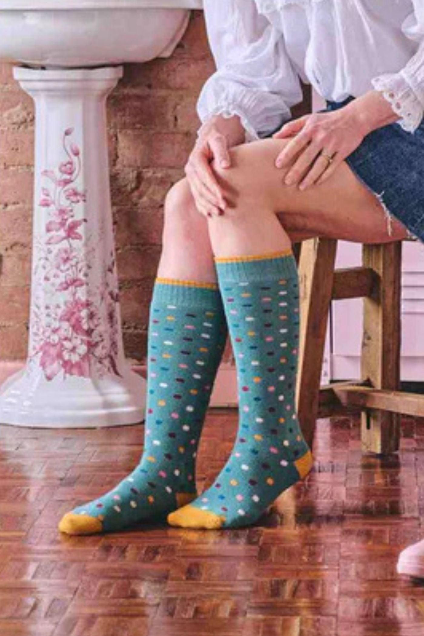 HJ Hall Women's Spotty Terrycloth Cotton Welly Socks in Teal – seated wearing socks