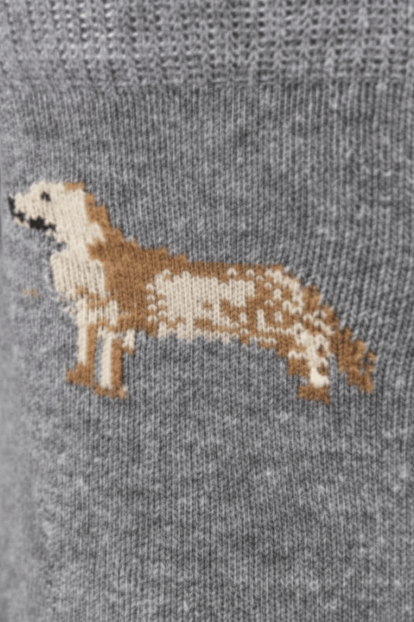 Close-up of a gray knit fabric featuring a knitted dog silhouette in tan and cream.